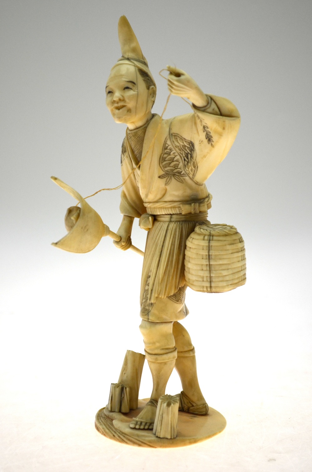 A Japanese Meiji period sectional carved ivory Okimono, fisherman with catching net (pole missing),