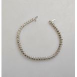 A diamond set line bracelet, white metal claw set fitted with safety catch,