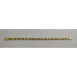 A yellow metal fancy linked bracelet alternately set with cabochon emeralds, sapphires and rubies,