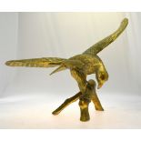 A large cast and hand forged brass eagle, spread-winged raised on a stylised branch base,