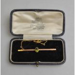 A yellow metal bar brooch set with oval peridot fitted with safety chain stamped 9ct in fitted box