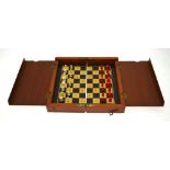 An early 20th century mahogany cased folding travel chess set with rosewood and boxwood board and