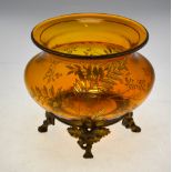 A French amber glass bowl decorated with gilded foliage raised on a metal mount with four acorn and