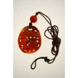 A Chinese chalcedony pendant carved with two dogs playing with a brocade ball, 42 mm long,