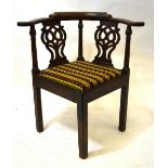 A George III mahogany corner elbow chair with fret cut splats over a cushion seat,