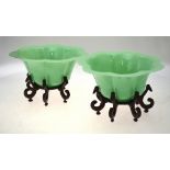 A pair of Peking green glass bowls of seven petal floral form c/w hardwood stands, circa 1920s,