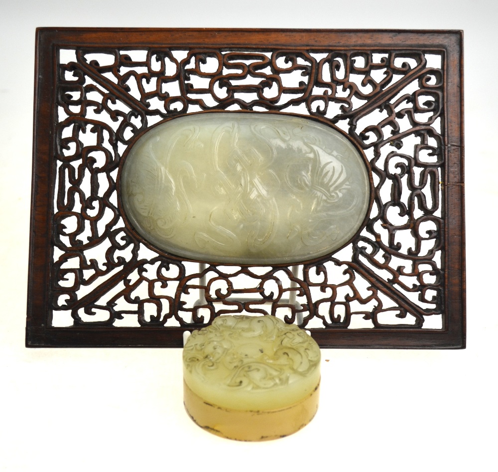 A Chinese oval pale jade plaque carved in shallow relief with auspicious objects (11.