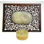 A Chinese oval pale jade plaque carved in shallow relief with auspicious objects (11.