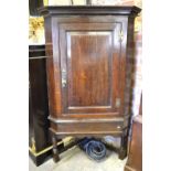 An 18th century oak corner cupboard with fielded panel single door, raised on a later low stand,