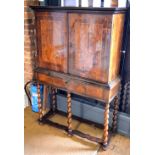 A 17th/18th century walnut cabinet on stand having a pair of figured wide cross-banded doors