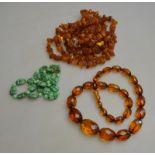 A long row of baroque amber beads to/w facetted beads and a row of green imitation scarab beads