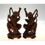 A pair of Chinese carved hardwood figures of ascetic Immortals riding a fabulous animal, 20 cm high,
