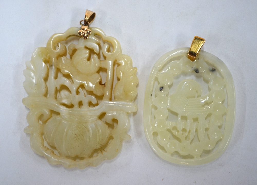 Two green jade pendants of reticulated form: one decorated with a flower arrangement;