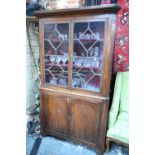 A George III oak two part standing corner cabinet,