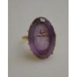 An oval amethyst set ring in yellow metal high claw setting,