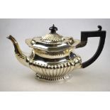 An Edwardian silver half-reeded tea pot of ogee form with ebony handle and finial,