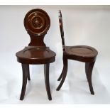 A pair of late Georgian mahogany hall chairs with circular moulded backs over shaped seats raised