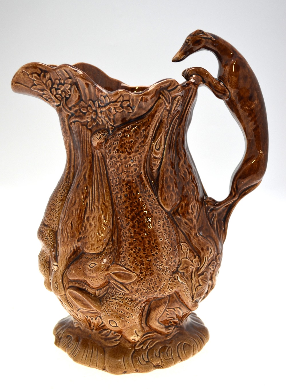 A 19th century brown glazed jug moulded with game - rabbits, ducks, fox, etc.