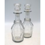 A pair of glass decanters and stoppers; each decanter with trumpet neck and oviform, faceted body,