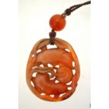 A Chinese chalcedony pendant carved with two dogs playing with a brocade ball, 42 mm long,