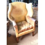 A Georgian style brass studded tan leather wing armchair,