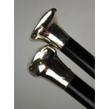 Two ebonised walking canes with silver pommels,