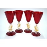 Four Venetian red writhen glass goblets with gold flecked swan moulded stems,