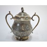 An Indian low-grade white metal sugar basin with hinged cover and twin handles,