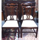 A set of four George III mahogany dining side chairs having shaped back rails over pierced vertical