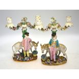 A pair of candlesticks, possibly Dresden; each one modelled as a standing boy beside a donkey,