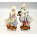 A pair of continental porcelain figures each beside a posy vase, raised on an oval base,