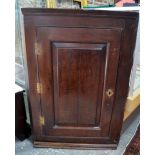 A 17th/18th century oak hanging corner cupboard, the fielded panel door enclosing shaped shelves,