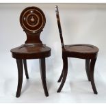 A pair of late Georgian mahogany hall chairs with circular moulded backs over shaped seats raised