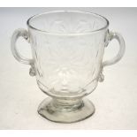 A late 18th/early 19th century glass loving cup having simple floral cut decoration raised on a