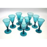 A set of nine blue cordial glasses, each one on cylindrical foot,