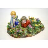 A Crown Staffordshire figural group of children on a mossy bank surrounded by groups of spring