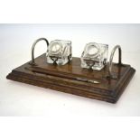 An oak ink stand with electro plated mounts and two glass ink-bottles with pen-rests,