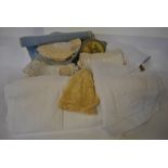 Two boxes containing a collection of linen and other tablecloths with crocheted edging,
