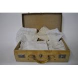 A vellum suitcase containing a finely embroidered linen tablecloth, a 'tatted' cotton tablecloth,