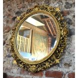 A late 19th century carved giltwood and gesso circular mirror set with scallop shells and curled