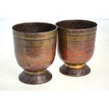 A pair of Indian or Persian metal stem cups, each one decorated with floral designs in red and gilt,
