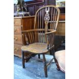 A late 19th century Windsor style armchair with wheel cut splat raised on turned legs united by