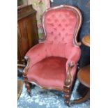 A Victorian mahogany framed serpentine armchair with red buttoned back upholstery,