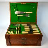 An oak canteen containing a quantity of electroplated fiddle pattern flatware and steel cutlery and