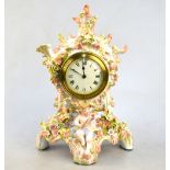 A floral-encrusted china mantel clock in the rococo manner, mounted with the figure of Cupid,