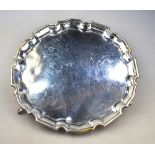 An Edwardian heavy quality silver card salver with pie-crust rim and three hoof feet,