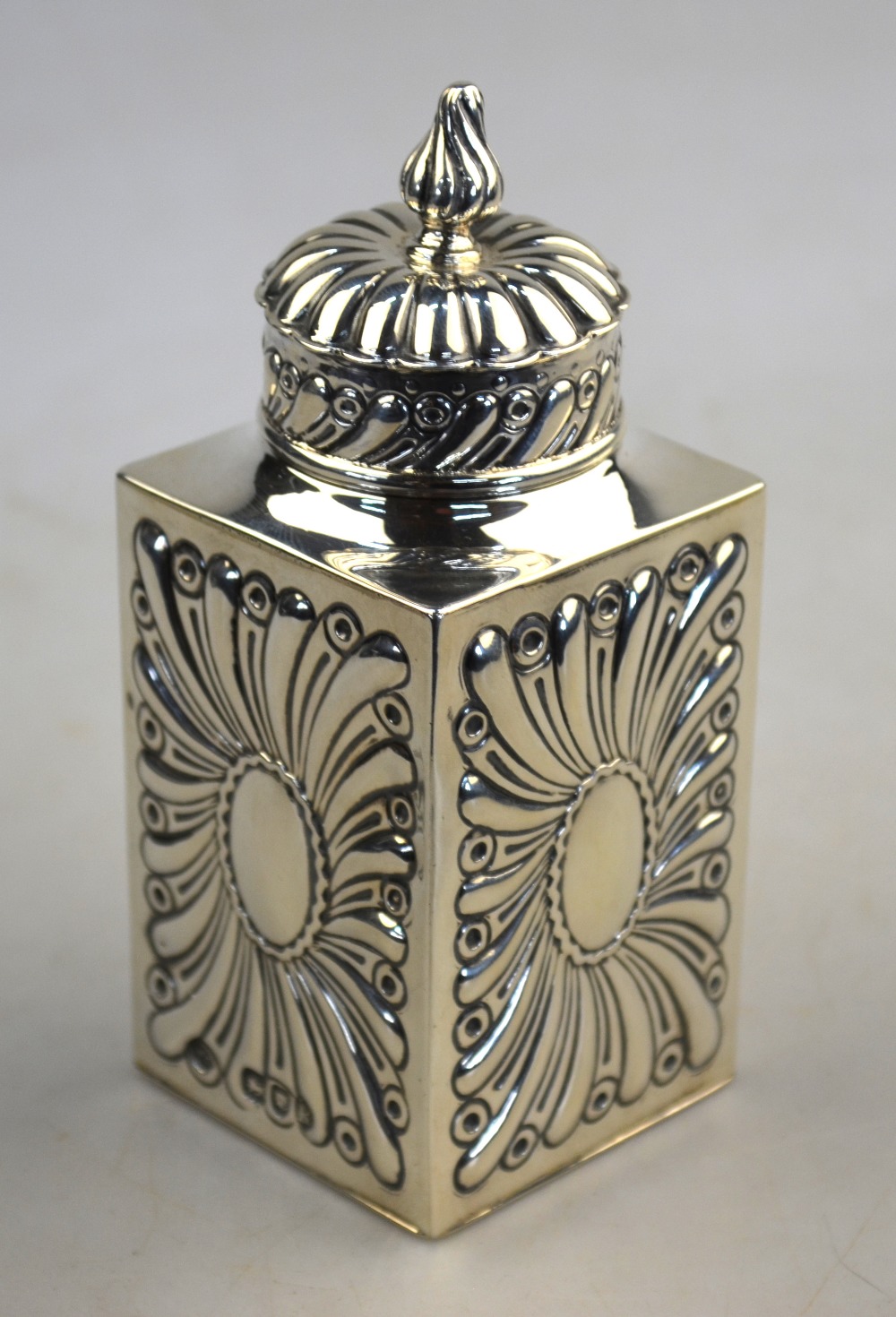 A Victorian embossed silver tea caddy of square form with domed cover, William Comyns & Sons,