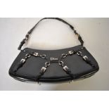 A Christian Dior navy blue leather shoulder bag of curved form with multi-buckled strap decoration,