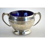 A silver two-handled sugar basin with ribbed waist and raised foot-rim, blue glass liner,