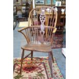 A 19th century elm seat Windsor hoop back Windsor elbow chair, with wheel cut splat,